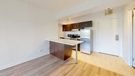 Located on Rue Sherbrooke Est in Montréal's vibrant Le Plateau-Mont-Royal area, this well-appointed one-bedroom, one-bathroom unit offers a functional and contemporary layout across a single floor. Light wood laminate flooring flows consistently throughout the living spaces, lending a clean and cohesive aesthetic to the interior.

The open-concept kitchen and living area forms the heart of the unit. The kitchen features dark espresso cabinetry, stainless steel appliances including a fridge and range, and a peninsula with a white countertop that doubles as a breakfast bar — ideal for casual dining or meal prep. The adjacent living area is bright and airy, benefiting from a large sliding window that frames lush treetop views and allows generous natural light to fill the space.

The bedroom is a comfortable, well-proportioned room with its own window overlooking greenery and the surrounding cityscape. A baseboard heating unit ensures year-round comfort, and a closet provides practical built-in storage.

The bathroom is finished with wood-toned floor tiles and matching wall tiling in the shower and tub surround. Dark wood cabinetry beneath the vanity complements the earthy palette, creating a warm and functional washroom.

Overall, the unit presents a bright, modern, and efficiently designed living space in a sought-after Montréal neighbourhood.