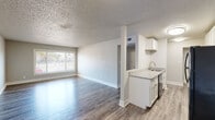 Located at 250 N Murray Blvd in Colorado Springs, Colorado, this single-floor unit presents a clean, updated interior with a thoughtfully arranged open layout. Wood-style plank flooring runs throughout the main living areas, lending a cohesive and contemporary feel, while neutral gray and white tones on the walls create a bright, airy atmosphere.

The kitchen is a functional highlight, featuring white cabinetry with brushed hardware, granite-style countertops, and black appliances including an electric range with overhead microwave and a full-size refrigerator. A peninsula with a sink and additional counter space connects the kitchen to the living area, providing an efficient transition between the two spaces. The living room is generously proportioned, with a large window that admits natural light and offers views of the surrounding neighborhood.

A hallway connects the main living areas to the bedroom, which is finished with plush carpet and includes an open closet with a full-width wire shelf and hanging rod. The bathroom is equipped with a tub-shower combination featuring a clean white surround and brushed nickel fixtures. Textured ceilings are consistent throughout the unit, and centralized HVAC vents ensure climate control in each area.