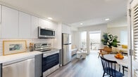 Located at 3170 W Olympic Blvd in Los Angeles, this modern single-floor unit offers a thoughtfully designed open-concept layout with clean lines and contemporary finishes throughout. Light wood-style flooring runs seamlessly through the space, complementing the bright, neutral color palette.

The kitchen is a standout feature, equipped with stainless steel appliances — including a refrigerator, electric range, over-the-range microwave, and dishwasher — paired with two-tone cabinetry featuring white upper cabinets and slate-blue lower cabinets. White quartz countertops and a classic subway tile backsplash complete the polished look.

The living area flows naturally from the kitchen, bathed in natural light from large windows and a glass door that opens to a private balcony with city views. The bedroom is generously proportioned, featuring large windows that flood the space with daylight, creating a bright and airy retreat.

The bathroom maintains the unit's modern aesthetic with a white quartz vanity, undermount sink, contemporary fixtures, a large wall mirror, and a tiled walk-in shower. Recessed lighting throughout the unit adds a clean, finished touch. This well-appointed space combines modern design with functional living in the heart of Los Angeles.