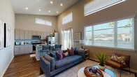 This single-floor residence makes a striking first impression with its dramatic, soaring ceilings that lend an expansive, airy quality to the open-concept living and kitchen area. Tall windows — including elevated clerestory windows — flood the space with abundant natural light, creating a bright and welcoming atmosphere throughout the day. Rich hardwood-style flooring flows seamlessly across the main living areas, grounding the design with warmth and continuity.

The kitchen is a standout feature, outfitted with light wood cabinetry that extends to the ceiling, granite-style countertops, stainless steel appliances, and a central island with a sink and bar seating — ideal for both cooking and casual dining. The open living room offers generous space for relaxation, framed by large windows with views of the surrounding neighborhood.

A sliding glass door connects the living area to an outdoor space, enhancing the sense of openness. The bathroom off the main area features granite countertops, modern fixtures, and hardwood-style flooring. The bedroom is a calm, well-lit retreat with a sizable closet, neutral tones, and a dedicated en-suite bathroom with a tub and vanity. Every detail in this residence reflects a thoughtful, contemporary design sensibility.