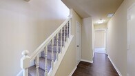 This three-bedroom, two-bathroom home is thoughtfully arranged across three floors, offering a practical and comfortable layout. The main living level features warm hardwood-style flooring throughout an open living area bathed in natural light from large sliding glass doors with vertical blinds, providing access to an outdoor space. The well-appointed kitchen is a standout feature, showcasing rich dark cabinetry, light countertops, a subway tile backsplash, stainless steel appliances including a gas range and refrigerator, and durable hardwood-style flooring.

The upper floors house all three bedrooms, each carpeted for comfort and equipped with built-in closets. The spacious primary bedroom includes a generous closet and access to built-in shelving, reflecting thoughtful storage design. The secondary bedrooms are well-sized, each with their own closet space and baseboard heating. Both bathrooms feature hardwood-style flooring, with one offering a tub-shower combination and a dark wood vanity, and the other a tub with a wall surround.

Connecting the floors are two staircases with classic white-spindle railings and carpeted treads, complemented by hallways with clean white trim and neutral warm-toned walls throughout. The overall ambiance is clean, neutral, and move-in ready.