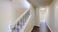 This three-bedroom, two-bathroom home is thoughtfully arranged across three floors, offering a practical and comfortable layout. The main living level features warm hardwood-style flooring throughout an open living area bathed in natural light from large sliding glass doors with vertical blinds, providing access to an outdoor space. The well-appointed kitchen is a standout feature, showcasing rich dark cabinetry, light countertops, a subway tile backsplash, stainless steel appliances including a gas range and refrigerator, and durable hardwood-style flooring.

The upper floors house all three bedrooms, each carpeted for comfort and equipped with built-in closets. The spacious primary bedroom includes a generous closet and access to built-in shelving, reflecting thoughtful storage design. The secondary bedrooms are well-sized, each with their own closet space and baseboard heating. Both bathrooms feature hardwood-style flooring, with one offering a tub-shower combination and a dark wood vanity, and the other a tub with a wall surround.

Connecting the floors are two staircases with classic white-spindle railings and carpeted treads, complemented by hallways with clean white trim and neutral warm-toned walls throughout. The overall ambiance is clean, neutral, and move-in ready.