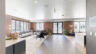 Located at 2287 Welton St in Denver's vibrant Five Points neighborhood, this well-appointed amenity lounge spans a single floor and offers a thoughtfully designed communal experience. The space is anchored by striking exposed red brick walls that contrast elegantly with crisp white ceilings and modern finishes throughout.

The lounge area features oversized sectional sofas, leather accent chairs, and a patterned area rug set atop geometric tile flooring, all bathed in abundant natural light from large floor-to-ceiling windows. French doors open directly to an outdoor courtyard with pool views, seamlessly blending indoor and outdoor living.

A central kitchen and bar area showcases a long waterfall-edge marble island with leather barstools, dark matte cabinetry, green subway tile accents, a built-in television, and a draft beer tap — ideal for gatherings and entertaining. A sleek service counter with mirrored upper cabinetry provides additional functionality.

Adjacent to the main lounge, a game room features a full shuffleboard table, high-top bar tables, navy wood-paneled walls, a gold-framed mirror, and bold abstract artwork, creating an intimate yet lively atmosphere. Built-in window nook seating offers cozy spots with direct views of the outdoor pool and courtyard, completing this dynamic and versatile community space.