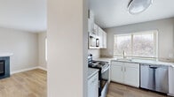 Located at 2552 Duportail St in Richland, WA, this 2-bedroom, 1-bathroom unit offers a well-organized, single-floor layout designed for comfortable everyday living. The living room serves as the heart of the home, featuring light-toned luxury vinyl plank flooring, a ceiling fan, and a tile-surround fireplace with a clean white mantel — a welcoming focal point complemented by a large window that brings in natural light and outdoor greenery views. The kitchen is efficiently designed with white shaker-style cabinetry, granite-look countertops, and a full suite of appliances including an electric range, built-in microwave, dishwasher, and a stainless steel sink positioned beneath a bright window. A dedicated laundry room houses a full-size washer and dryer, adding notable convenience. The bathroom features a wide vanity with granite-look countertops, white cabinetry, and a large wall mirror. Both bedrooms are carpeted in neutral tones and receive natural light through sizable windows with exterior views. A connecting hallway ties the layout together efficiently. The unit's consistent neutral palette, updated finishes, and functional room arrangement make it a practical and comfortable residence.
