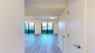 This contemporary two-story residence in Boston, MA offers three bedrooms and two bathrooms across two well-proportioned floors. The main level features an open-concept kitchen and living area bathed in natural light, with large sliding glass doors leading to a private balcony that overlooks the surrounding cityscape. The kitchen is outfitted with stainless steel appliances, including a French door refrigerator, a sleek range, and a built-in microwave. Cabinetry blends white upper cabinets with wood-toned lower panels, complemented by a light quartz peninsula with an undermount sink—ideal for both cooking and casual dining. Light hardwood flooring extends seamlessly throughout both levels, lending warmth and continuity to the space. The living area is bright and open, anchored by dual sliding glass doors that frame sweeping outdoor views. The upper floor houses the bedrooms, including a generously sized primary bedroom with large windows and access to the balcony. The bathrooms feature clean, modern finishes with textured tile surrounds and soaking tubs. Hallways connect the rooms with ease, and the overall design emphasizes a clean, minimalist aesthetic with a neutral palette throughout.