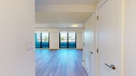 This contemporary two-story residence in Boston, MA offers three bedrooms and two bathrooms across two well-proportioned floors. The main level features an open-concept kitchen and living area bathed in natural light, with large sliding glass doors leading to a private balcony that overlooks the surrounding cityscape. The kitchen is outfitted with stainless steel appliances, including a French door refrigerator, a sleek range, and a built-in microwave. Cabinetry blends white upper cabinets with wood-toned lower panels, complemented by a light quartz peninsula with an undermount sink—ideal for both cooking and casual dining. Light hardwood flooring extends seamlessly throughout both levels, lending warmth and continuity to the space. The living area is bright and open, anchored by dual sliding glass doors that frame sweeping outdoor views. The upper floor houses the bedrooms, including a generously sized primary bedroom with large windows and access to the balcony. The bathrooms feature clean, modern finishes with textured tile surrounds and soaking tubs. Hallways connect the rooms with ease, and the overall design emphasizes a clean, minimalist aesthetic with a neutral palette throughout.