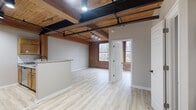 Located at 101 Whiting St in Winsted, CT, this 2-bedroom, 1-bathroom unit showcases a compelling blend of industrial character and modern updates. The open living area immediately impresses with its warm wood-planked ceiling, exposed wooden beams, and bold black steel conduit running overhead, all complemented by track lighting. Original exposed red brick walls add historic texture, while large multi-pane windows invite natural light and offer views of surrounding trees. Light-toned luxury vinyl plank flooring runs throughout, tying the space together cohesively. The kitchen features warm wood cabinetry, a white subway tile backsplash, granite countertops, stainless steel appliances, and a peninsula that opens to the living area. The primary bedroom is a well-proportioned retreat showcasing the same exposed brick and wood-beam ceiling, with a closet providing built-in storage. The second bedroom also features the signature wood-beam ceiling and includes a closet. The bathroom is clean and functional, equipped with a full tub-shower combination. A hallway connects the rooms efficiently. This unit's industrial-chic aesthetic, characterized by its raw architectural elements paired with contemporary finishes, creates a uniquely characterful living space.