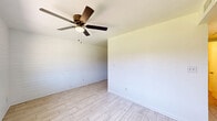 Located at 510 N Horne in Mesa, AZ, this single-story 2-bedroom, 1-bathroom unit offers a clean, bright interior defined by white-painted brick walls and light wood-look tile flooring throughout. The open living area provides a simple, airy feel with white walls that maximize the sense of space.

The kitchen is well-appointed with gray shaker-style cabinetry, striking dark marble-look countertops, a stainless steel electric range, and a full-size refrigerator — all set against light tile flooring that runs seamlessly through the unit. A range hood and ample upper and lower cabinet storage add practical functionality.

Both bedrooms feature the same white-painted brick accent walls and wood-look tile floors, lending a cohesive aesthetic throughout. Each room is filled with natural light from windows that offer views of surrounding trees and the neighborhood. The bedrooms include built-in closets with bifold doors, providing useful storage. The primary bedroom connects conveniently to the hallway.

The bathroom includes a full tub-shower combination with a white surround, brushed nickel fixtures, and a small window for ventilation and natural light.

Outside, a generously sized yard with mature trees and greenery provides a private outdoor retreat — a notable feature for a residence of this scale in the Mesa area.