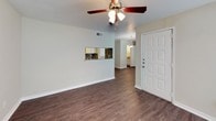 This two-story residence offers a well-organized layout with distinct living spaces across both levels. The main floor centers around a living area finished with dark hardwood-style flooring and a ceiling fan overhead. A stone-surround fireplace serves as a focal point, flanked by windows that bring in natural light. A pass-through window connects the living area to the kitchen, enhancing the open feel between spaces.

The galley-style kitchen is thoughtfully appointed with white cabinetry, granite countertops, a stainless steel double sink, and a mosaic tile backsplash in earth tones of brown, tan, and black. Dark hardwood-style flooring continues through the kitchen, which opens into a hallway leading to additional rooms.

Upstairs, carpeted bedrooms provide a comfortable retreat, each equipped with ceiling fans. One bedroom features a window for natural light, while another includes access to a spacious walk-in closet with built-in shelving on multiple walls. The staircase landing is defined by a white-painted half-wall with a handrail.

The bathroom features a white vanity with granite countertops, a mosaic tile backsplash mirroring the kitchen's design, a well-lit mirror with a multi-bulb fixture, and a clean white shower enclosure with tiled walls.