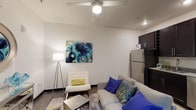 This two-story loft offers a thoughtfully designed open-concept layout that seamlessly blends living, dining, and kitchen areas on the main floor. The living space features polished concrete floors, a ceiling fan, and contemporary décor, creating a modern and inviting atmosphere. The kitchen is well-appointed with dark espresso cabinetry reaching floor to ceiling, granite countertops, and a full suite of stainless steel appliances, including a refrigerator, range, microwave, and dishwasher. A bold open staircase with wooden treads and dark metal framing serves as both a functional and architectural centerpiece, leading to the upper loft level. The upper floor hosts the bedroom area, complete with warm hardwood flooring, exposed industrial ductwork that adds an urban character, and a metal railing that overlooks the main living space. A full bathroom with granite countertops, dark cabinetry, and a shower-tub combination is conveniently located on this level. The main floor also includes a half bathroom featuring granite counters and matching dark cabinetry, consistent with the overall design aesthetic. Throughout the space, clean white walls, recessed lighting, and a cohesive modern industrial style create a balanced and comfortable environment.