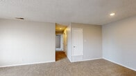 This single-floor, 2-bedroom, 1-bathroom residence offers a practical and well-organized layout designed for comfortable everyday living. The living room serves as the central gathering space, featuring neutral-toned carpet, a textured ceiling, and a front entry door alongside a window that allows natural light to filter in. A floor vent provides climate control throughout the open area.

The galley-style kitchen is efficiently designed with warm oak cabinetry lining both walls, white laminate countertops, a single-basin sink, a gas range, and a dishwasher. Durable wood-look flooring runs throughout the kitchen, complementing the cabinetry tones.

Both bedrooms are carpeted and finished with neutral walls and white trim. Each room features a window fitted with blinds for light control, and ceiling fans for added comfort. The primary bedroom, the larger of the two, offers direct access to both a walk-in closet with built-in shelving and the shared full bathroom. The bathroom includes a tub-shower combination with white tile surround, a toilet, and wood-look flooring.

An additional closet provides supplementary storage. Throughout the residence, clean white six-panel doors, consistent neutral tones, and textured ceilings create a cohesive and understated aesthetic.