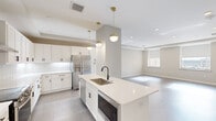 Located at 119 E Sixth St in the heart of downtown Tulsa, Oklahoma, this thoughtfully designed 2-bedroom, 2-bathroom residence offers a seamless blend of modern aesthetics and functional living. The open-concept kitchen and living area serves as the centerpiece of the home, featuring white shaker cabinetry, quartz countertops, a bold geometric tile backsplash, stainless steel appliances, and a large center island with a undermount sink — all illuminated by stylish gold pendant lighting and recessed fixtures. Tray ceilings add architectural depth throughout, while durable wood-look flooring flows through the main living areas. The spacious living room benefits from natural light through large windows and offers generous room for a variety of furniture arrangements. The primary bedroom is notably expansive, finished with plush patterned carpet, a ceiling fan, a tray ceiling, and direct access to a private bathroom. The well-appointed bathrooms feature white vanities with quartz countertops, matte black hardware, large mirrors, and marble-look tile flooring. A dedicated laundry area with in-unit washer adds everyday convenience. A hallway and closet provide additional storage, completing this well-organized and refined urban residence.