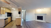 This single-floor residence offers a well-organized layout with a cohesive blend of modern finishes and functional design. The open living area serves as the heart of the unit, featuring durable wood-look flooring, crown molding, and a classic white-mantled fireplace that anchors the space. A hallway connects the living area to the private rooms, maintaining a clear and efficient flow throughout.

The galley-style kitchen is outfitted with light wood cabinetry, white quartz-style countertops, and stainless steel appliances including an electric range, microwave, refrigerator, and dishwasher. A pass-through peninsula provides a visual connection to the living area.

The bedrooms feature plush carpeting, vertical blind-covered windows that allow ample natural light, and generous closet space. One bedroom includes an adjacent bathroom with a wide quartz vanity, large mirror, and a walk-in glass-door shower. A second bathroom offers a similarly styled vanity with a full-width mirror and warm overhead lighting.

A dedicated laundry area houses a full-size washer and dryer alongside a water heater, adding everyday convenience. The unit's neutral color palette and clean finishes create a bright, move-in-ready atmosphere throughout.