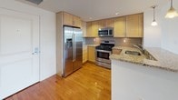 Located at 26 Haven St in Reading, MA, this single-floor residence offers a thoughtfully designed layout with contemporary finishes throughout. The open living area is bright and welcoming, showcasing gleaming hardwood floors, crisp white walls, and a modern track lighting fixture. Large windows and glass balcony doors flood the space with natural light while providing pleasant views of the surrounding neighborhood, with direct access to an outdoor balcony.

The kitchen is well-appointed with light maple cabinetry, granite countertops, a mosaic tile backsplash, and a full suite of stainless steel appliances including a gas range, built-in microwave, refrigerator with ice maker, and dishwasher. A peninsula with pendant lighting connects the kitchen to the living area, creating an open and functional flow ideal for everyday living and entertaining.

The bedroom features plush carpeting, a large window that invites ample natural light, and a serene, neutral color palette. The bathroom is finished with tile flooring, a granite-topped vanity with double sinks, light maple cabinetry, and a full tub-shower combination with decorative mosaic tile accents. Consistent hardwood flooring and clean architectural details tie the entire space together cohesively.