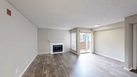 This single-floor residence offers three bedrooms, two full bathrooms, a combined kitchen and living area, two closets, and an in-unit laundry room. The open living room is a standout space, featuring rich wood-look flooring, a classic white-mantled fireplace, and a sliding glass door that opens to a private balcony, allowing natural light to fill the room. Neutral gray walls and a textured ceiling complete the comfortable, modern aesthetic.

The kitchen is efficiently designed with white cabinetry, light stone-look countertops, a tile backsplash, and black GE appliances including an electric range, over-the-range microwave, and refrigerator — all set on wood-look flooring that flows through the common areas.

Both bathrooms are clean and functional, each featuring a tiled tub-shower combination, white vanity with granite-style countertops, and wood-look flooring. The bedrooms are carpeted for comfort; one features a ceiling fan with light fixture and a bright window, while another offers access to a spacious walk-in closet with built-in shelving and rod systems. The primary bedroom provides a quiet retreat at a comfortable scale. This home balances practical functionality with a cohesive, neutral design throughout.