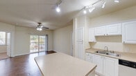 This well-appointed 2-bedroom, 2-bathroom single-story residence at 7895 Shadow Creek Dr in Hamilton, Ohio offers a thoughtfully designed open-concept layout. The entrance flows into a spacious living and dining area, where rich wood-look flooring and a ceiling fan create a welcoming atmosphere, with sliding glass doors opening to a private balcony. The kitchen is a functional highlight, featuring white cabinetry, a central peninsula with a light-toned countertop, stainless steel appliances including a refrigerator and range, track lighting, and tile flooring. A dedicated dining area is accented by a stylish pendant light. Both bedrooms are finished with plush carpet and neutral walls; the second bedroom benefits from dual windows that invite natural light and outdoor views. The two bathrooms feature tile flooring, vanity storage, and clean, neutral finishes. Additional practical spaces include a dedicated laundry room with washer and dryer hookups and built-in shelving, as well as two closets for ample storage. The warm, neutral color palette throughout creates a cohesive, move-in-ready environment suited for comfortable everyday living.