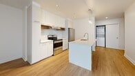 Located at 9675 Avenue Papineau in Montréal, this well-appointed 2-bedroom, 1-bathroom unit offers a thoughtfully designed single-floor layout with a clean, contemporary aesthetic throughout. Light wood laminate flooring runs continuously across all living areas, complementing the crisp white walls and modern finishes that define the space.

The kitchen is a standout feature, showcasing tall white cabinetry, a striking marble-effect tile backsplash, stainless steel appliances including a range and French door refrigerator, and a sleek white waterfall-edge island with an integrated sink and pendant lighting. In-unit laundry is conveniently tucked nearby.

The open living area benefits from large floor-to-ceiling windows that invite abundant natural light and offer views of the surrounding neighbourhood. A wall-mounted mini-split unit provides efficient climate control. The primary bedroom is a generously proportioned retreat with large sliding glass doors opening to an outdoor area, while the second bedroom features its own window and baseboard heating.

The bathroom is finished with large-format neutral tiles, a soaking tub with tiled surround, a separate glass shower, and a wood-accented vanity. A dedicated closet and an entry hall with storage complete this well-organized, move-in-ready home.