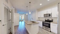 Located at 111 Grove Park Dr in Mooresville, NC, this single-floor home offers five bedrooms and two bathrooms with a clean, modern aesthetic throughout. The open-concept kitchen and living area serves as the heart of the home, featuring a large center island with a undermount sink, pendant lighting, quartz-style countertops, white shaker cabinetry, a classic subway tile backsplash, and stainless steel appliances including a range, microwave, and French-door refrigerator. Wood-look plank flooring runs seamlessly throughout the entire home, lending warmth and cohesion to every room. The living area is bright and airy, highlighted by French doors that invite natural light and provide outdoor access, complemented by a ceiling fan overhead. Each of the five bedrooms is comfortably sized, with the generously proportioned primary bedroom offering ample space. Bedrooms feature ceiling fans, neutral walls, and windows with blinds. The two bathrooms are finished with white cabinetry, quartz-style countertops, undermount sinks, and glass-enclosed walk-in showers. A central hallway connects the bedrooms and bathrooms, maintaining an efficient and functional layout throughout this well-appointed Mooresville home.