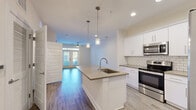 Located at 111 Grove Park Dr in Mooresville, NC, this single-floor home offers five bedrooms and two bathrooms with a clean, modern aesthetic throughout. The open-concept kitchen and living area serves as the heart of the home, featuring a large center island with a undermount sink, pendant lighting, quartz-style countertops, white shaker cabinetry, a classic subway tile backsplash, and stainless steel appliances including a range, microwave, and French-door refrigerator. Wood-look plank flooring runs seamlessly throughout the entire home, lending warmth and cohesion to every room. The living area is bright and airy, highlighted by French doors that invite natural light and provide outdoor access, complemented by a ceiling fan overhead. Each of the five bedrooms is comfortably sized, with the generously proportioned primary bedroom offering ample space. Bedrooms feature ceiling fans, neutral walls, and windows with blinds. The two bathrooms are finished with white cabinetry, quartz-style countertops, undermount sinks, and glass-enclosed walk-in showers. A central hallway connects the bedrooms and bathrooms, maintaining an efficient and functional layout throughout this well-appointed Mooresville home.