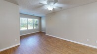 This single-floor, 2-bedroom, 2-bathroom residence offers a practical and comfortable layout designed to maximize everyday living. The open-concept kitchen and living area serves as the heart of the home, featuring warm hardwood-style flooring, a textured ceiling, and a ceiling fan with integrated lighting. A large window invites abundant natural light, creating a bright and welcoming atmosphere. The kitchen is equipped with rich honey-toned wood cabinetry, a full suite of white appliances including a range, microwave, and refrigerator, and a peninsula with a laminate countertop and stainless steel sink — ideal for casual dining or meal prep. Both bedrooms are finished with plush wall-to-wall carpeting, ceiling fans, and windows that bring in natural light. The primary bedroom offers a generous footprint with direct access to its own bathroom. Each of the two bathrooms features a full tub-and-shower combination with white tile surround, chrome fixtures, and hardwood-style flooring. A dedicated laundry room houses a full-size washer and dryer with an overhead storage shelf, adding everyday convenience. Two closets provide ample storage throughout. Neutral-toned walls and consistent finishes lend a cohesive, move-in-ready feel to the entire space.