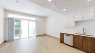 Located at 1265 Stearns Dr in the heart of Los Angeles, this modern single-floor residence offers a clean, contemporary design throughout. Light wood-tone flooring flows seamlessly across the entire unit, complementing the crisp white walls and recessed lighting that create a bright, airy atmosphere.

The open-concept living area is a standout feature, bathed in natural light streaming through floor-to-ceiling sliding glass doors that lead to a private balcony. A transom window above the doors adds additional brightness and visual height to the space.

The kitchen is thoughtfully designed with a two-tone cabinet scheme — sleek white upper cabinets paired with rich dark wood lower cabinets — and durable white countertops. Stainless steel appliances, including a gas range, built-in microwave, dishwasher, and French door refrigerator, provide a fully equipped culinary space.

The bedroom offers a quiet, well-proportioned retreat with ample natural light and direct sightlines to the kitchen area. An additional room serves flexibly as a second bedroom or office. The bathroom is finished with warm wood-toned tile surrounds, a soaking tub and shower combination, a dark wood vanity, and an illuminated LED mirror, delivering a spa-like aesthetic. The unit combines modern finishes with functional design in a prime Los Angeles location.