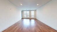 Located at 704 Williamson St in Madison, WI, this well-appointed one-bedroom, one-bathroom unit offers a thoughtfully designed open-concept layout. The combined kitchen and living area serves as the heart of the home, showcasing rich hardwood flooring, crisp white walls, and recessed lighting throughout. The modern kitchen is a standout feature, equipped with dark espresso cabinetry, granite countertops, a large central island with a built-in sink, stainless steel appliances including a refrigerator, range, and microwave, and stylish pendant lighting overhead. The spacious living area flows seamlessly from the kitchen and is bathed in natural light through a bank of large windows offering outdoor views. A wide hallway with recessed lighting connects the living spaces to the private bedroom, which features plush carpeting, a ceiling fan, and windows that allow ample natural light. The bedroom includes access to a generously sized walk-in closet fitted with multi-level wire shelving. The bathroom offers a clean, neutral aesthetic with a full tub-shower combination and tile-style flooring. This unit combines contemporary finishes with a practical, comfortable layout.