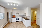Located in Edmonton's vibrant Oliver neighbourhood, this one-bedroom, two-bathroom unit offers a thoughtfully designed layout across a single floor. The kitchen is a standout feature, showcasing crisp white shaker-style cabinetry extending to the ceiling, dark countertops, a subway tile backsplash, and a full suite of stainless steel appliances including a refrigerator, electric range, and dishwasher. Light wood-tone vinyl plank flooring runs throughout, complementing the bright and clean aesthetic. A window in the kitchen allows natural light to filter in, adding to the airy feel of the space. The bedroom is a comfortable size, featuring a large sliding-door closet, neutral-toned walls, and a window with views of the surrounding neighbourhood. Additional storage is provided through three closets distributed throughout the unit. Both bathrooms are finished in a clean, functional style, with one featuring a full tiled tub-and-shower surround, a vanity with dark countertop, and a mirrored medicine cabinet. A hallway connects the rooms efficiently, contributing to a well-organized flow. Baseboard heating is present throughout. The unit offers a practical and updated living space well-suited to those seeking comfort and convenience in central Edmonton.