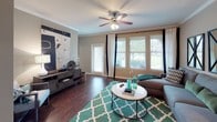 This 2-bedroom, 2-bathroom single-story residence offers a thoughtfully designed layout that balances comfort and functionality. The living area is a welcoming space featuring rich hardwood flooring, crown molding, and a ceiling fan with light fixture. Large windows allow abundant natural light to fill the room, while a sliding glass door provides access to the outdoors and views of the surrounding greenery.

The kitchen is equipped with warm wood cabinetry, a double stainless steel sink, white appliances including a range and built-in microwave, and ample counter space. Crown molding adds an elegant touch, and under-cabinet lighting enhances the workspace.

Both bedrooms are generously sized with plush carpeting, crown molding, and ceiling fans. Each features a walk-in closet, providing excellent storage. The primary bedroom connects to a private en-suite bathroom complete with a soaking tub, tiled surround, a wood vanity, and a large mirror. The second bathroom features a glass-enclosed walk-in shower, a wood vanity with a single sink, and tile flooring. The overall ambiance throughout the residence is warm, neutral, and inviting.