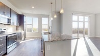 Located at 5909 Sharpsburg Dr in Madison, Wisconsin, this single-floor residence offers a thoughtfully designed open-concept layout filled with natural light. Large windows throughout the living and dining areas frame sweeping outdoor views of the surrounding landscape, while light-toned hardwood flooring ties the space together seamlessly.

The kitchen is a standout feature, showcasing rich dark cabinetry, granite countertops with subtle veining, a classic white subway tile backsplash, and a full suite of stainless steel appliances including a refrigerator, range, and built-in microwave. A spacious central island with a stainless steel sink and elegant pendant lighting above serves as both a functional workspace and a natural gathering point. The kitchen opens directly to the living area, which benefits from an abundance of sunlight streaming through floor-to-ceiling sliding glass doors that lead to a private outdoor deck.

The bathroom is well-appointed with a granite-topped double vanity, dark cabinetry matching the kitchen, and a walk-in shower. A dedicated closet with built-in shelving and carpeted flooring provides generous storage. The overall design is clean, contemporary, and cohesive, making this a well-equipped and comfortable residence in Madison.