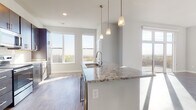 Located at 5909 Sharpsburg Dr in Madison, Wisconsin, this single-floor residence offers a thoughtfully designed open-concept layout filled with natural light. Large windows throughout the living and dining areas frame sweeping outdoor views of the surrounding landscape, while light-toned hardwood flooring ties the space together seamlessly.

The kitchen is a standout feature, showcasing rich dark cabinetry, granite countertops with subtle veining, a classic white subway tile backsplash, and a full suite of stainless steel appliances including a refrigerator, range, and built-in microwave. A spacious central island with a stainless steel sink and elegant pendant lighting above serves as both a functional workspace and a natural gathering point. The kitchen opens directly to the living area, which benefits from an abundance of sunlight streaming through floor-to-ceiling sliding glass doors that lead to a private outdoor deck.

The bathroom is well-appointed with a granite-topped double vanity, dark cabinetry matching the kitchen, and a walk-in shower. A dedicated closet with built-in shelving and carpeted flooring provides generous storage. The overall design is clean, contemporary, and cohesive, making this a well-equipped and comfortable residence in Madison.
