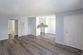 Located at 11843 Gilmore St in North Hollywood, Los Angeles, this single-floor unit offers a clean, functional layout with modern finishes throughout. The open-concept living and dining area is finished with wood-look laminate flooring, soft gray walls, and a textured ceiling. A ceiling fan provides comfortable airflow, while large sliding glass doors and windows allow natural light to fill the space and provide access to the outdoors. A wall-mounted A/C unit ensures climate control year-round. The galley-style kitchen is thoughtfully designed with white shaker cabinets, a mosaic tile backsplash, light stone countertops, a stainless steel gas range, and a stainless steel refrigerator, all set along parallel walls that maximize efficiency. A pass-through peninsula connects the kitchen to the living area, enhancing the open feel. The bedroom is a quiet, well-proportioned room with the same laminate flooring, ample wall space, and a closet. The bathroom features a full tub-shower combo with a curtain, toilet, and vanity, all finished with clean white fixtures and durable wood-look flooring. The overall ambiance is bright, neutral, and move-in ready.