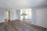 Located at 11843 Gilmore St in North Hollywood, Los Angeles, this single-floor unit offers a clean, functional layout with modern finishes throughout. The open-concept living and dining area is finished with wood-look laminate flooring, soft gray walls, and a textured ceiling. A ceiling fan provides comfortable airflow, while large sliding glass doors and windows allow natural light to fill the space and provide access to the outdoors. A wall-mounted A/C unit ensures climate control year-round. The galley-style kitchen is thoughtfully designed with white shaker cabinets, a mosaic tile backsplash, light stone countertops, a stainless steel gas range, and a stainless steel refrigerator, all set along parallel walls that maximize efficiency. A pass-through peninsula connects the kitchen to the living area, enhancing the open feel. The bedroom is a quiet, well-proportioned room with the same laminate flooring, ample wall space, and a closet. The bathroom features a full tub-shower combo with a curtain, toilet, and vanity, all finished with clean white fixtures and durable wood-look flooring. The overall ambiance is bright, neutral, and move-in ready.