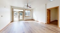Located at 218 Wolfe St in Oregon, Wisconsin, this single-floor, 2-bedroom, 1-bathroom home offers a well-designed layout with consistent light hardwood flooring throughout. The open-concept kitchen and living area serves as the heart of the home, where a peninsula with a double sink and warm cherry-toned cabinetry flows seamlessly into a bright living room. The living room is equipped with a ceiling fan and features a large window and glass door that invite abundant natural light and views of the outdoors. The kitchen is outfitted with white appliances, including a refrigerator, range, and built-in microwave, complemented by ample upper cabinetry and light countertops. The spacious primary bedroom benefits from natural light and direct access to a generous walk-in closet with wrap-around shelving and hardwood floors. The second bedroom also features hardwood flooring, a ceiling fan, and a window with outdoor views. The full bathroom is finished with large-format tile flooring and includes accessibility features such as grab bars at the toilet and bathtub. Track lighting in key areas and warm wood trim throughout lend the space a cohesive, inviting character.