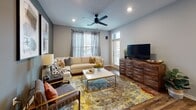 This single-floor residence offers a thoughtfully designed layout that balances open communal spaces with private retreats. The open-concept kitchen and dining area serves as the heart of the home, featuring white cabinetry, stainless steel appliances, a subway tile backsplash, and a central island with bar seating — all set atop rich hardwood-style flooring that flows throughout the main living areas. Recessed lighting illuminates the space, while an adjacent dining area provides room for entertaining.

The living room is warm and inviting, anchored by a ceiling fan, large windows that draw in natural light, and a door providing additional access to the exterior. Abstract wall art and layered textiles contribute to a contemporary, curated aesthetic.

Two bedrooms offer comfortable retreats, each carpeted and naturally lit by windows with views to the outside. The primary bedroom features a ceiling fan and a warm wood headboard, while the second bedroom is anchored by a striking four-poster bed frame with gold-accented posts.

Each bathroom is finished with wood-style flooring, light cabinetry, and clean gray walls. The primary bath connects directly to a walk-in closet, adding practical storage. A second full bathroom includes a tub-shower combination.