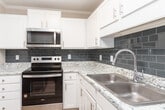 Located at 1522 Bridford Pkwy in Greensboro, NC, this single-floor unit offers a well-designed layout with a thoughtful mix of finishes and functional spaces throughout.

The kitchen is a standout feature, showcasing crisp white cabinetry, granite-look countertops, a slate-blue subway tile backsplash, and a full suite of stainless steel appliances, including a dishwasher and microwave. Light wood-style flooring runs through the kitchen and connects seamlessly to adjoining areas.

Living and bedroom spaces are generously sized, with neutral-toned walls and ceiling fans with light fixtures providing comfort and versatility. Several rooms feature plush carpeting, while others continue the warm hardwood-style flooring. Multiple windows dressed with horizontal blinds invite natural light and outdoor views into the living areas.

The bathroom is clean and functional, featuring a full tub-shower combo with a curved curtain rod, wood-style flooring, and a towel bar for added convenience.

A dedicated laundry area includes a full-size washer and dryer alongside a bi-fold closet door and overhead shelving, maximizing storage efficiency. Throughout the unit, textured ceilings, clean white trim, and a consistent neutral color palette contribute to a bright, move-in-ready atmosphere.
