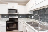 Located at 1522 Bridford Pkwy in Greensboro, NC, this single-floor unit offers a well-designed layout with a thoughtful mix of finishes and functional spaces throughout.

The kitchen is a standout feature, showcasing crisp white cabinetry, granite-look countertops, a slate-blue subway tile backsplash, and a full suite of stainless steel appliances, including a dishwasher and microwave. Light wood-style flooring runs through the kitchen and connects seamlessly to adjoining areas.

Living and bedroom spaces are generously sized, with neutral-toned walls and ceiling fans with light fixtures providing comfort and versatility. Several rooms feature plush carpeting, while others continue the warm hardwood-style flooring. Multiple windows dressed with horizontal blinds invite natural light and outdoor views into the living areas.

The bathroom is clean and functional, featuring a full tub-shower combo with a curved curtain rod, wood-style flooring, and a towel bar for added convenience.

A dedicated laundry area includes a full-size washer and dryer alongside a bi-fold closet door and overhead shelving, maximizing storage efficiency. Throughout the unit, textured ceilings, clean white trim, and a consistent neutral color palette contribute to a bright, move-in-ready atmosphere.