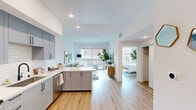 Located at 850 N Azusa Ave in Azusa, California, this well-appointed one-bedroom, one-bathroom unit offers a bright and efficiently designed living space across a single floor. Light wood-tone flooring runs throughout, creating a warm, cohesive aesthetic complemented by crisp white walls and recessed lighting.

The open-concept kitchen and living area form the heart of the unit. The kitchen is outfitted with gray shaker-style cabinetry, a white subway tile backsplash, stainless steel appliances including a French door refrigerator, electric range, microwave, and dishwasher, and a generous quartz waterfall island that doubles as a breakfast bar. The living room flows naturally from the kitchen and is anchored by large sliding glass doors that open to a private balcony, flooding the space with natural light and providing a charming outdoor retreat.

The bedroom is spacious and serene, featuring a wide bank of windows that invite abundant daylight and views of the surrounding neighborhood. A dedicated closet offers practical storage, and the room's clean lines lend a calm, restful atmosphere.

The bathroom continues the unit's modern aesthetic with gray cabinetry, a white countertop, and tiled shower walls. A welcoming entry foyer with recessed lighting completes this thoughtfully designed urban home.