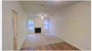 Located at 1878 E Nine Mile Rd in Pensacola, Florida, this single-floor space offers a comfortable and well-lit layout designed for easy living. The main living area is a standout feature, showcasing a combination of warm hardwood flooring and plush carpeting that defines the central gathering space. Two large windows flank a classic fireplace, flooding the room with abundant natural light and creating an inviting, airy atmosphere. A ceiling fan is centrally positioned overhead, enhancing comfort and airflow throughout the room. The walls are finished in a clean, neutral tone that complements the light-filled environment and provides a versatile backdrop for any décor style. The vaulted ceiling adds a sense of openness and volume to the living space, contributing to the overall spacious feel of the interior. The textured ceiling detail adds subtle architectural character, while the clean lines and simple finishes throughout give the space a move-in-ready appeal. This single-story layout offers practical, accessible living in a well-established Pensacola neighborhood.