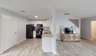 Located at 2903–2909 N Buckner Blvd in Dallas, Texas, this two-story residence offers a thoughtfully designed interior with a clean, contemporary aesthetic carried throughout. The main level features an open-concept layout connecting the kitchen, living, and dining areas, creating a cohesive and functional space. The kitchen is equipped with white shaker-style cabinetry, black appliances including a refrigerator, electric range, and over-the-range microwave, and a peninsula with a built-in sink that overlooks the living area. Light wood-look flooring extends across the main level, complementing the soft gray walls and crisp white trim. The dining area benefits from natural light through window treatments and provides direct access to an exterior door. A bright sitting or office area on the main floor features a large window that draws in ample natural light. Upstairs, the bedrooms are carpeted and offer dedicated closet space, with the primary bedroom featuring a walk-in closet. The bathrooms are clean and functional, with one featuring a tiled tub-and-shower combination with marble-style surround, and another serving as a half bath with a white vanity. Textured ceilings and consistent finishes throughout give the home a cohesive, move-in-ready feel.