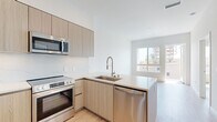 This modern 2-bedroom, 2-bathroom residence in San Diego's 92103 neighborhood offers a thoughtfully designed open-concept layout with a clean, contemporary aesthetic throughout. Light wood-tone flooring runs seamlessly across the entire space, enhancing the bright and airy ambiance created by abundant natural light from well-placed windows.

The kitchen serves as the heart of the home, featuring a peninsula with a quartz countertop, an undermount sink with a pull-down faucet, light wood cabinetry, a marble-style backsplash, and a full suite of stainless steel appliances including a refrigerator, electric range, over-the-range microwave, and dishwasher. The kitchen flows directly into the living area, which benefits from a large window and access to an outdoor balcony.

Both bedrooms are well-proportioned and sun-filled, each offering views of the surrounding neighborhood. The primary bedroom connects to a full bathroom with a light wood vanity, quartz countertop, large mirror, and a tile-surround shower, as well as a dedicated walk-in closet with wraparound shelving and hanging rods. The second bathroom features a matching vanity design and reflects the same refined, minimalist style. An in-unit stacked washer and dryer is also conveniently included.