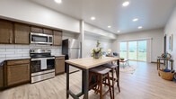 Located on S Heritage Way in Andover, Kansas, this well-appointed 2-bedroom, 2-bathroom residence offers a thoughtfully designed single-floor layout with modern finishes throughout. Light-toned luxury vinyl plank flooring runs continuously through the main living areas, creating a cohesive and clean aesthetic.

The open-concept kitchen, dining, and living area serves as the heart of the home. The kitchen is outfitted with rich dark wood cabinetry, granite countertops, a white subway tile backsplash, and a full suite of stainless steel appliances including a refrigerator, range, and microwave. A bar-height dining table bridges the kitchen and living space seamlessly. The living room is bright and airy, anchored by large sliding glass doors that flood the room with natural light and open to an outdoor balcony with scenic views of the surrounding landscape.

The primary bedroom is a comfortable retreat featuring a large window with expansive outdoor views, a ceiling fan, and warm wood-toned flooring. The primary bathroom includes a granite-topped double vanity with ample cabinetry. A dedicated laundry room houses an in-unit washer, water heater, and HVAC system for added convenience. The second bedroom offers a flexible space suitable for a guest room or home office. A dedicated closet and additional storage round out this well-organized residence.
