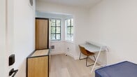 Located at 2315 College Avenue in the heart of Berkeley, CA, this two-bedroom unit offers a clean, modern design across a single floor. The space features light wood-toned flooring throughout, crisp white walls, and recessed lighting that create a bright, contemporary atmosphere.

The primary bedroom is the larger of the two rooms, benefiting from a charming bay window arrangement that allows natural light to filter in while offering views of surrounding greenery. The bay window nook provides a natural spot for a desk setup, making it well-suited for studying or working from home. Wood-paneled cabinetry adds warmth and practical storage to the room.

The secondary bedroom is a more intimate, efficiently designed space with recessed ceiling lighting and clean white walls. It comfortably accommodates a bed and a compact desk, making it a functional personal retreat.

A connecting hallway links the two bedrooms and leads to the unit's entry door, which features a modern keypad lock. The overall design aesthetic is minimal and functional, with consistent light wood flooring and neutral tones carried throughout. This unit's location near UC Berkeley makes it well-positioned for students and academics seeking a streamlined, move-in ready living space.