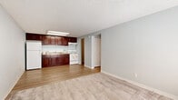 Located at 965 Candle Light Blvd in Brooksville, Florida, this single-floor unit offers a practical and well-organized layout. The open-concept living and kitchen area is finished with a combination of wood-look vinyl flooring and plush carpet, creating a clear distinction between spaces. The kitchen is equipped with rich dark mahogany cabinetry, stone-patterned countertops, a double stainless steel sink, a white electric range, and a full-size refrigerator, all illuminated by overhead lighting and a textured ceiling. The living area is bright and airy, benefiting from a window that allows natural light to fill the room, complemented by a front entry door and a low built-in storage console beneath the windowsill. The bedroom is generously sized with soft carpeting, a textured ceiling, and a large reach-in closet with double doors and wire shelving, providing ample storage. The full bathroom features a dark wood vanity with a white countertop, a combined tub and shower, and wood-look flooring, delivering a clean and functional finish. A dedicated utility room houses the water heater and provides additional space for laundry hookups, adding everyday convenience to this well-appointed unit.