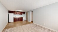 Located at 965 Candle Light Blvd in Brooksville, Florida, this single-floor unit offers a practical and well-organized layout. The open-concept living and kitchen area is finished with a combination of wood-look vinyl flooring and plush carpet, creating a clear distinction between spaces. The kitchen is equipped with rich dark mahogany cabinetry, stone-patterned countertops, a double stainless steel sink, a white electric range, and a full-size refrigerator, all illuminated by overhead lighting and a textured ceiling. The living area is bright and airy, benefiting from a window that allows natural light to fill the room, complemented by a front entry door and a low built-in storage console beneath the windowsill. The bedroom is generously sized with soft carpeting, a textured ceiling, and a large reach-in closet with double doors and wire shelving, providing ample storage. The full bathroom features a dark wood vanity with a white countertop, a combined tub and shower, and wood-look flooring, delivering a clean and functional finish. A dedicated utility room houses the water heater and provides additional space for laundry hookups, adding everyday convenience to this well-appointed unit.