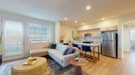 This well-appointed single-floor residence in Brentwood, CA (94513) offers a thoughtfully designed open-concept layout with modern finishes throughout. The living area is bright and welcoming, featuring light hardwood-style flooring, recessed lighting, and large windows with blinds that invite generous natural light. A glass door opens to an outdoor area, further enhancing the airy ambiance. The living space flows seamlessly into the kitchen, which is equipped with light wood cabinetry, white quartz countertops, stainless steel appliances including a full-size refrigerator and electric range, and a peninsula with bar seating — ideal for casual dining or entertaining. The bedrooms are calm and comfortable, each featuring large windows with outdoor views, light flooring, and closet storage. The bathrooms are clean and contemporary, finished with light wood vanities, white quartz countertops, large mirrors, and tub-shower combinations with tile surrounds. The overall aesthetic is modern and cohesive, with a neutral color palette, consistent flooring, and recessed lighting carried throughout the home, creating a unified and inviting atmosphere from room to room.