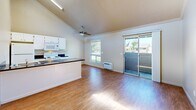 Located at 6232 N Pershing Ave in Stockton, CA, this one-bedroom, one-bathroom unit offers a well-designed single-level layout that maximizes its cozy footprint. The open-concept kitchen and living area is the heart of the home, highlighted by impressive vaulted ceilings that lend a sense of spaciousness well beyond its physical size. Warm wood-look flooring flows throughout the main living areas, complementing the neutral, beige-toned walls.

The kitchen features white cabinetry, dark granite countertops, a central island with a built-in sink, and white appliances including a refrigerator, electric range, and built-in microwave. A high clerestory window above the kitchen floods the space with natural light. The living area benefits from a ceiling fan, a wall-mounted AC unit, and a sliding glass door that opens onto a private balcony with pleasant neighborhood views.

The bedroom is a comfortable retreat with soft carpeting, crown molding, and a large window framing lush greenery outside. The bathroom is clean and functional, featuring wood-look flooring, a combined tub and shower enclosed with sliding glass doors, and neutral wall tones. A hallway connects the main living spaces with efficient flow throughout the unit.