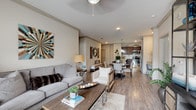 This single-floor residence offers a thoughtfully designed open-concept layout that seamlessly connects the living, dining, and kitchen areas. The living room features warm wood-look flooring, crown molding, a ceiling fan, and generous natural light from large windows. The kitchen is a standout feature, showcasing rich dark wood cabinetry, granite countertops, a subway tile backsplash, stainless steel appliances, and a peninsula island with pendant lighting — ideal for both cooking and casual dining. A dedicated desk nook adjacent to the kitchen provides a convenient workspace. The dining area flows naturally between the kitchen and living room, creating an inviting space for entertaining. The bedroom is generously proportioned, with plush carpet, a ceiling fan, and bright windows that bring in natural light. The primary bathroom features dark wood vanity cabinetry with granite counters, wood-look flooring, and direct access to a spacious walk-in closet. A secondary bathroom mirrors the same refined finishes and also offers closet access. Completing the unit is a dedicated in-unit laundry area with a full-size washer and dryer. Throughout, a neutral color palette and consistent high-quality finishes create a cohesive, comfortable living environment.