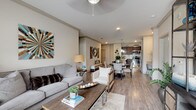 This single-floor residence offers a thoughtfully designed open-concept layout that seamlessly connects the living, dining, and kitchen areas. The living room features warm wood-look flooring, crown molding, a ceiling fan, and generous natural light from large windows. The kitchen is a standout feature, showcasing rich dark wood cabinetry, granite countertops, a subway tile backsplash, stainless steel appliances, and a peninsula island with pendant lighting — ideal for both cooking and casual dining. A dedicated desk nook adjacent to the kitchen provides a convenient workspace. The dining area flows naturally between the kitchen and living room, creating an inviting space for entertaining. The bedroom is generously proportioned, with plush carpet, a ceiling fan, and bright windows that bring in natural light. The primary bathroom features dark wood vanity cabinetry with granite counters, wood-look flooring, and direct access to a spacious walk-in closet. A secondary bathroom mirrors the same refined finishes and also offers closet access. Completing the unit is a dedicated in-unit laundry area with a full-size washer and dryer. Throughout, a neutral color palette and consistent high-quality finishes create a cohesive, comfortable living environment.