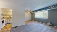 Located at 8380 Pearl Rd in Strongsville, Ohio, this single-floor residence offers a well-organized layout with a practical mix of living spaces. The main living area is generously sized, featuring soft wall-to-wall carpeting, a textured ceiling, and a ceiling fan for year-round comfort. A large window with vertical blinds fills the space with natural light and provides pleasant views of surrounding greenery, while a teal accent wall adds a distinctive touch of color. Adjacent bedroom areas mirror this comfortable aesthetic, each with carpeting, windows with natural light, and direct access to closet or bathroom spaces. The kitchen is efficiently designed with white cabinetry, stone-look countertops, wood-look flooring, and white appliances including a range and dishwasher. The bathrooms are thoughtfully updated, showcasing teal-toned vanities with white countertops, wood-look flooring, and cool blue-grey wall tones that create a cohesive, calming atmosphere throughout. Connecting hallways and entry areas transition smoothly between the carpeted and hard-surface flooring zones. Overall, the space presents a clean, neutral palette with carefully chosen accent colors, offering a functional and comfortable living environment in the Strongsville community.
