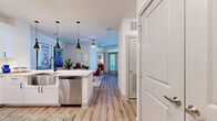 This thoughtfully laid-out 2-bedroom, 2-bathroom residence offers a cohesive blend of modern design and functional living across a single floor. Light wood-tone flooring runs throughout the main living areas, anchoring the open-concept kitchen and living room. The kitchen is a standout feature, equipped with stainless steel appliances including a French door refrigerator, built-in microwave, and range. Crisp white shaker cabinetry, a classic subway tile backsplash, and a spacious peninsula with bar seating create an ideal space for both meal prep and casual dining. Striking black pendant lights hang above the peninsula, adding a contemporary accent. The living area benefits from a ceiling fan and natural light filtering in through large windows and glass doors. The primary bedroom offers a comfortable footprint with plush carpet, built-in shelving, and direct access to a generously sized walk-in closet with custom shelving and storage systems. The second bedroom is bright and airy, featuring a ceiling fan and a large window. Both bathrooms are finished with white vanities, clean countertops, and a glass-enclosed shower. Two dedicated closets enhance the overall storage capacity of this well-appointed residence.